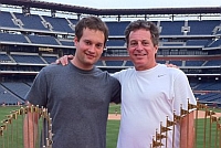 Ryan Goldstein and his dad at Citizens Bank Park with the Phillies' World Series trophies from 2008 and 1980